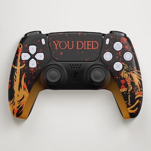Peut inclure: Manette noire PlayStation 5 avec un design personnalisé. La manette affiche le texte "YOU DIED" en rouge, avec des accents orange et rouges. Le design comprend une ancre et une figurine de guerrier.