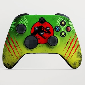 May include: A custom Xbox controller with a green and yellow gradient design, featuring a red circle with a black dinosaur silhouette. The controller has red claw marks and green fern accents.