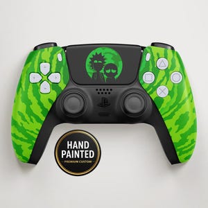 Puede incluir: Un mando de videojuegos negro pintado a medida con detalles en verde. El mando presenta un patrón de sandía verde en los laterales y un gráfico de dibujos animados en el panel central. Un adhesivo circular dice "HAND PAINTED - PREMIUM CUSTOM".