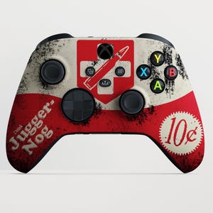 Peut inclure: Une manette Xbox personnalisée avec un design rouge, blanc et noir. La manette présente le texte "Drink Juggernog" et un graphique de balle. Les boutons sont noirs et les boutons de face sont colorés.