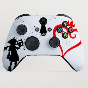 Può includere: Un controller per videogiochi bianco con la sagoma nera di un personaggio che tiene un'arma a forma di chiave sul lato sinistro, un'icona a forma di serratura nera al centro e un grande cuore rosso con una corona sul lato destro.