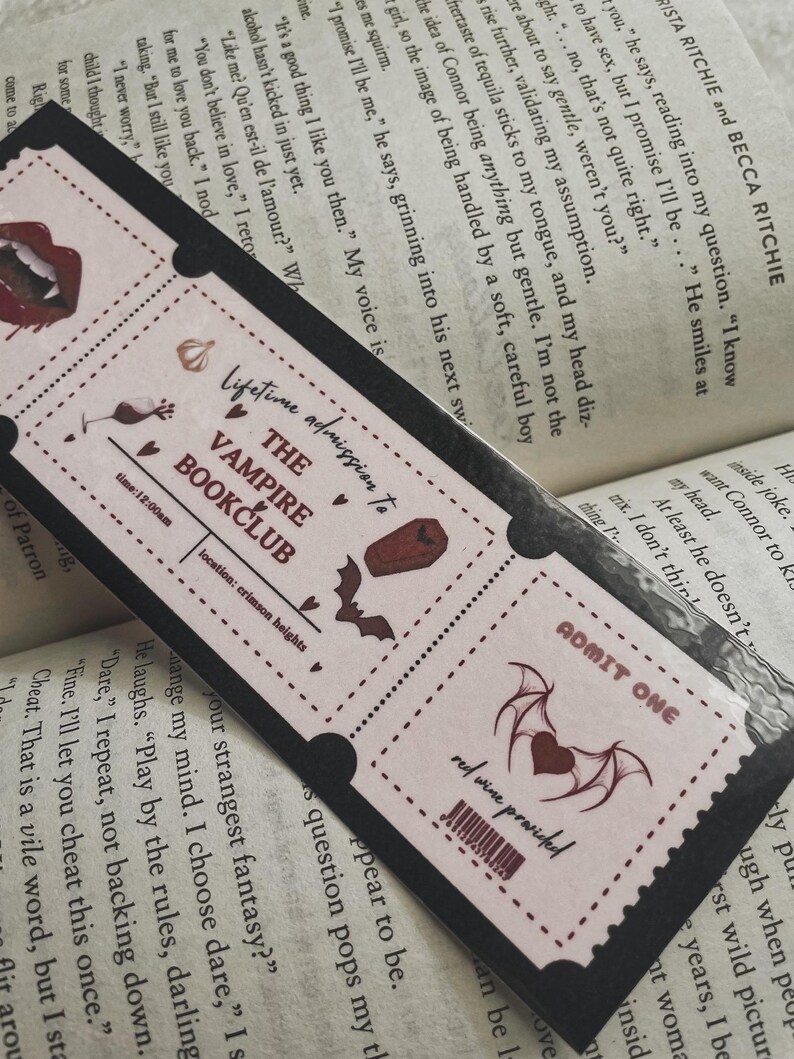 Może przedstawiać: R&oacute;żowy i czarny bilet z tekstem "Dożywotnie członkostwo w Vampire Bookclub" i czerwonym sercem z nietoperzowymi skrzydłami. Bilet ma kod kreskowy i tekst "wino czerwone w cenie".