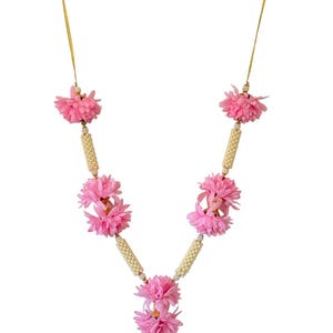 May include: A pink floral garland with white beaded detailing and a gold-coloured string for hanging. The garland features clusters of pink flowers and is designed in a V-shape.
