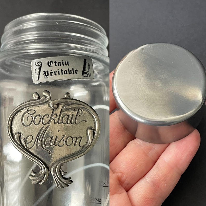 May include: A clear glass cocktail shaker with a metal lid. The shaker has a decorative metal label that reads "Cocktail Maison" and "Etain V&eacute;ritable". The lid is a solid, brushed metal.