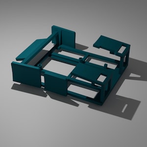 May include: A teal-colored, 3D-printed rectangular frame with various structural components. The frame has a box-like shape with several rectangular panels and support beams. The object casts a shadow on a light gray surface.