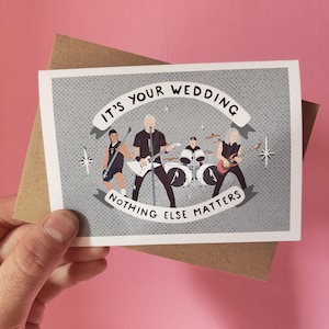 May include: A greeting card with a band illustration. The card features a gray background with the text "IT'S YOUR WEDDING" and "NOTHING ELSE MATTERS" in a banner. The band is depicted playing instruments. The card is held in a hand.