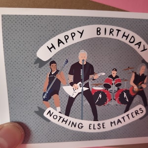 May include: Birthday card featuring a band illustration. The band members are depicted playing instruments against a gray dotted background. The words "Happy Birthday" and "Nothing Else Matters" are written on the card.