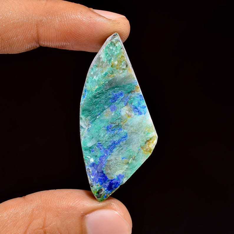 Puede incluir: Una piedra preciosa verde y azul con una forma irregular y &aacute;spera. La piedra preciosa tiene una apariencia transl&uacute;cida con una mezcla de colores verde, azul y blanco.