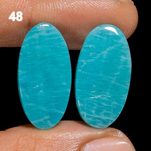 May include: Two oval-shaped turquoise gemstones with a white marbled pattern. The stones are smooth and polished.