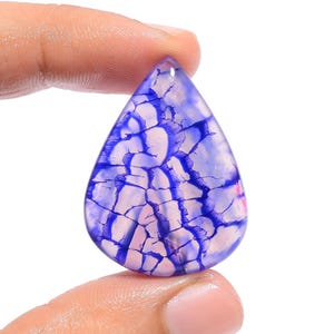May include: A teardrop-shaped cabochon gemstone with a white base and a blue and purple dendritic pattern.