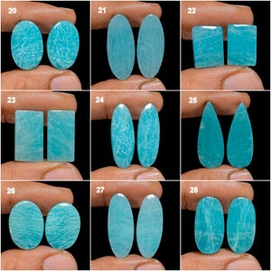 May include: A set of 28 cabochon gemstones, each with a unique shape and pattern. The gemstones are a light blue color with white veins running through them. The gemstones are arranged in rows of two, with each row labeled with a number from 20 to 28.