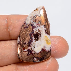 Pode incluir: Uma pedra preciosa caboch&atilde;o em forma de l&aacute;grima, de cor branca, marrom e cobre. A pedra preciosa tem um padr&atilde;o &uacute;nico de inclus&otilde;es de cobre.