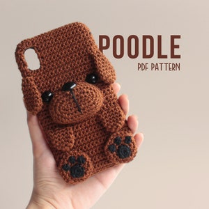 Może przedstawiać: Brązowy, szydełkowy pokrowiec na telefon w kształcie pudla z czarnymi odciskami łapek. Pokrowiec ma efekt 3D, a głowa pudla wystaje. Tekst "POODLE PDF PATTERN" jest napisany brązowymi literami na białym tle.