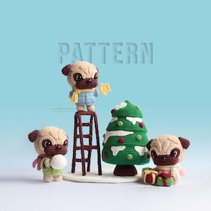 Op de afbeelding: Drie gehaakte pug-hondenspeelgoed, één op een ladder die een ster op een groene gehaakte kerstboom plaatst, een ander die een sneeuwbal vasthoudt en de derde die een cadeaudoos vasthoudt.