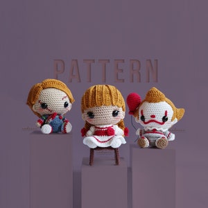Może przedstawiać: Trzy szydełkowe lalki inspirowane postaciami z horrorów. Lalki obejmują Chucky'ego, Annabelle i Pennywise'a. Każda lalka ma unikalny design, z Chucky'm trzymającym nóż, Annabelle w białej sukience i Pennywise'em trzymającym czerwony balon. Słowo "PATTERN" znajduje się w tle.