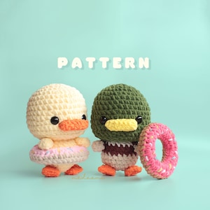 Puede incluir: Dos juguetes amigurumi de crochet, un pato amarillo y un pato verde, ambos con accesorios en forma de donut rosa y blanco. La palabra "PATTERN" está escrita en letras blancas sobre un fondo azul claro.