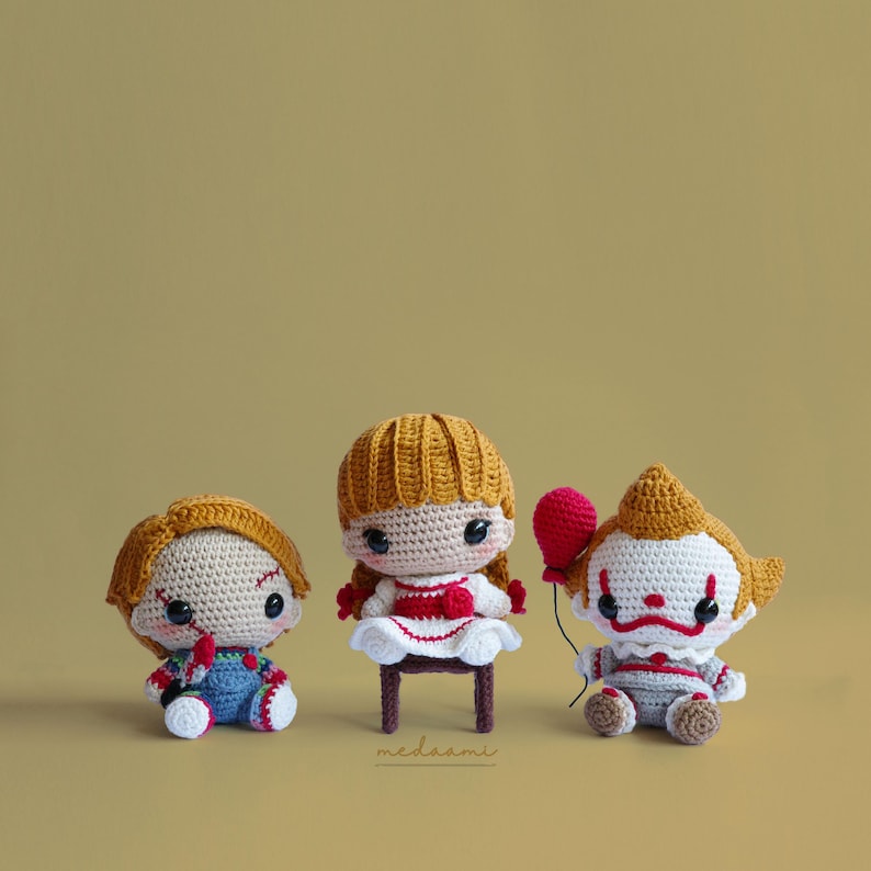 Peut inclure: Trois peluches en crochet inspir&eacute;es de personnages de films d'horreur. Une fille avec une robe rouge et blanche, un gar&ccedil;on avec une salopette bleue et un clown avec un ballon rouge.