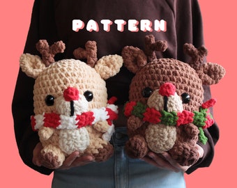 May include: Two crocheted reindeer ornaments, one brown and one cream, with red and green yarn accents. The reindeer are wearing festive scarves and are holding a green and red garland.