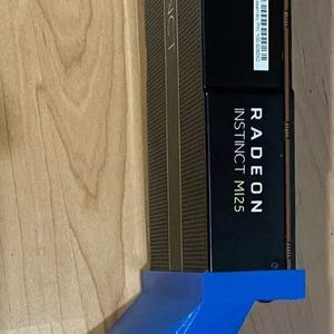 Peut inclure: Une carte graphique Radeon Instinct M125 noire et dorée avec un support bleu. La carte porte l'inscription "Radeon Instinct M125" et "Radeon Instinct". Le support est de couleur bleu vif.