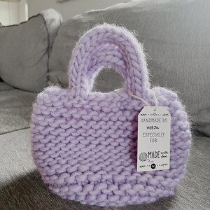 K&ouml;nnte beinhalten: Eine lavendelfarbene Stricktasche mit einem wei&szlig;en Etikett, auf dem "Handmade by HeeJu Especially for Made with love" steht.