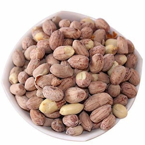 May include: A white bowl filled with shelled peanuts. The peanuts are a mix of tan and light brown, with some partially shelled, revealing the yellow nut inside. The image is well-lit, highlighting the texture and color of the nuts.