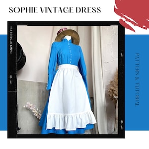 Op de afbeelding: Een vintage blauwe jurk met een witte schort. De jurk heeft lange mouwen, een hoge kraag en kleine knopen aan de voorkant. De witte schort heeft een gefranjerde zoom. De tekst "SOPHIE VINTAGE DRESS" staat bovenaan.