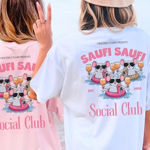 Könnte beinhalten: Rosa und weiße T-Shirts mit einer Grafik von Cartoon-Mäusen mit Sonnenbrillen, die Getränke halten. Der Text "SAUFI SAUFI" und "Social Club" ist auf die Shirts gedruckt.