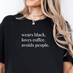 Könnte beinhalten: Ein schwarzes T-Shirt mit weißem Text, der "wears black. loves coffee. avoids people." lautet.