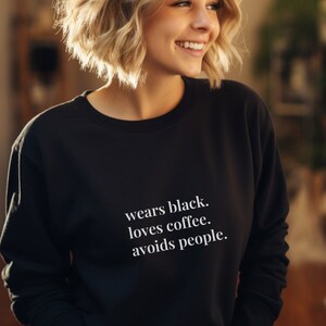 Könnte beinhalten: Ein schwarzer Pullover mit weißem Text, der "wears black. loves coffee. avoids people." lautet.