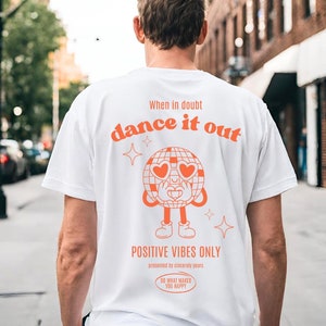 Könnte beinhalten: Weißes T-Shirt mit einer orangefarbenen Grafik einer Discokugel mit herzförmigen Sonnenbrillen und dem Text "When in doubt dance it out" und "Positive Vibes Only".