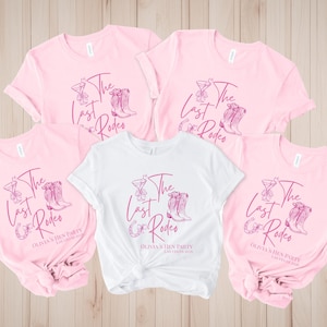 Peut inclure: Plusieurs t-shirts roses et blancs avec un motif sur le thème du rodéo. Le motif comprend un verre à cocktail, des bottes de cow-boy et le texte "The Last Rodeo" et "Olivia's Hen Party Las Vegas 2020".