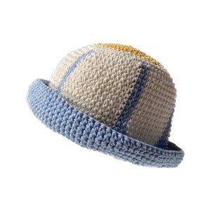 May include: A crocheted bucket hat with a light blue brim and accents. The hat's main body is off-white with blue and yellow stripes. The hat is made of a textured yarn, and the brim is a solid light blue color.