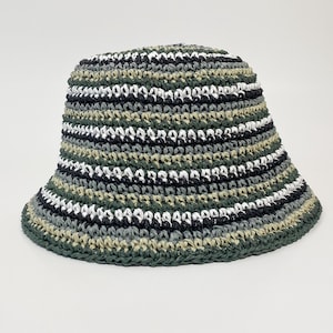 Puede incluir: Un sombrero de pescador hecho a mano con ala ancha. El sombrero est&aacute; tejido a ganchillo con rayas horizontales alternas de hilo verde, negro, blanco y gris. Un accesorio casual.