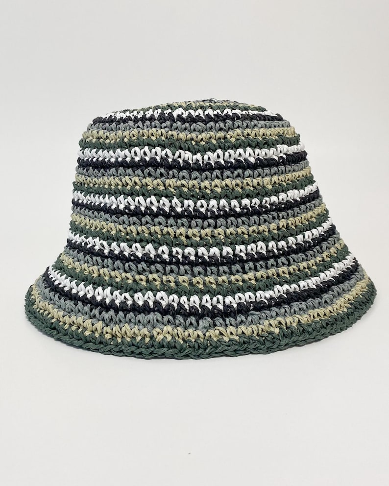 Puede incluir: Un sombrero de pescador hecho a mano con ala ancha. El sombrero est&aacute; tejido a ganchillo con rayas horizontales alternas de hilo verde, negro, blanco y gris. Un accesorio casual.