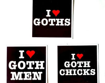 Può includere: Tre adesivi quadrati neri con testo bianco e un cuore rosso. Gli adesivi dicono "Amo ♥ i gotici", "Amo ♥ gli uomini gotici" e "Amo ♥ le ragazze gotiche".