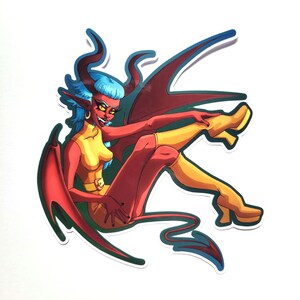 May include: A sticker featuring a cartoon illustration of a red-skinned demon with blue hair and horns. The demon is wearing a yellow outfit and boots, with red wings and a tail. The demon is smiling and has yellow eyes.