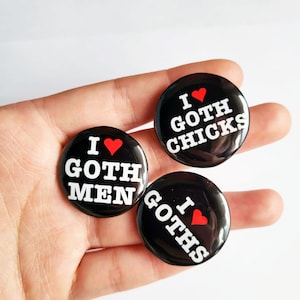 May include: Three black button pins with white text and a red heart. The pins say "I love Goth Chicks", "I love Goth Men", and "I love Goths".