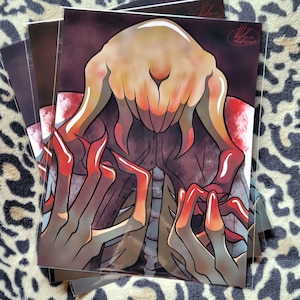 May include: A stack of art prints featuring a grotesque, stylized creature with a pale, fleshy head and long, red-tipped claws. The artwork has a dark, ominous color palette with shades of brown, red, and beige.