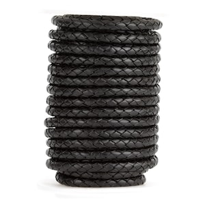 May include: A roll of black braided leather cord. The cord is tightly wound and is approximately 2.5 cm in diameter.