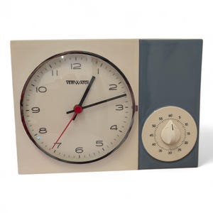 Puede incluir: Un reloj VeriWatch vintage con una esfera color crema y un panel lateral azul. El reloj tiene manecillas negras, un segundero rojo y un dial de temporizador. La esfera del reloj tiene números negros y una cubierta de vidrio.