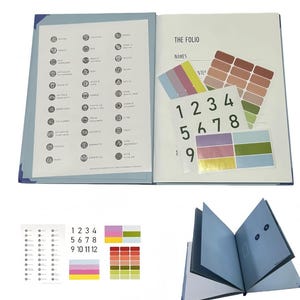 May include: A blue document organiser folio titled THE FOLIO, featuring an internal list of categories with icons, a sheet of numbered stickers from 1 to 12, and multiple sets of rectangular colour-coded adhesive labels in various shades.