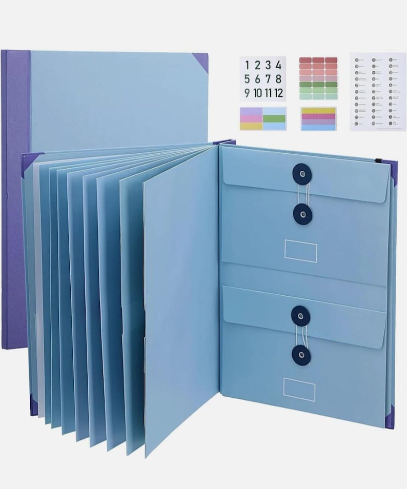 May include: A light blue expanding file folder with multiple interior dividers, two front pockets secured by dark blue string-and-button closures, and a set of adhesive labels featuring numbers 1 through 12 and various coloured tabs.