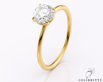 May include: A gold solitaire engagement ring with a round brilliant cut diamond.