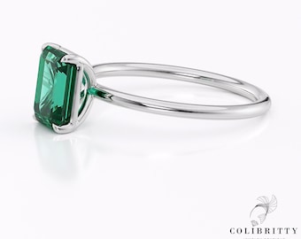 Op de afbeelding: Een zilveren ring met een grote smaragdgroene edelsteen in een kraalbezetting.