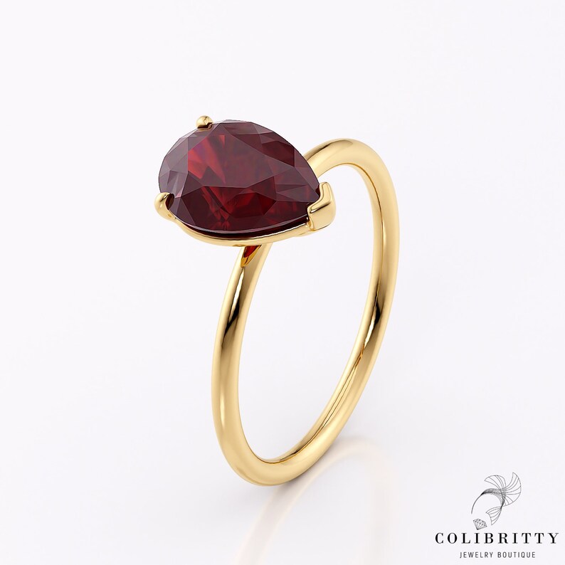 May include: A gold ring with a pear-shaped red gemstone.