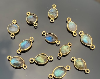 May include: Twelve gold-toned oval-shaped gemstone connector charms with two jump rings. The gemstones are iridescent blue, green, and gold.