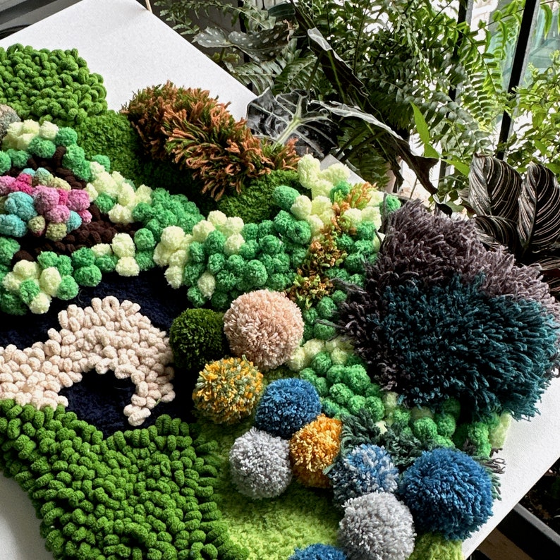 May include: A green, blue, and white pom-pom rug with a variety of textures. The rug is made of yarn and has a variety of shapes and sizes. The rug is a great way to add a touch of whimsy to any room.