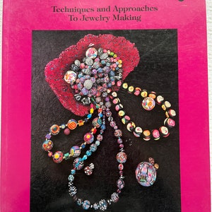 May include: Book cover with the title "The New Clay: Techniques and Approaches to Jewelry Making" by Nan Roche. The cover features a colorful image of polymer clay beads and jewelry.