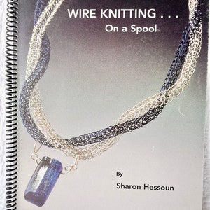 May include: A book titled "WIRE KNITTING... On a Spool" by Sharon Hessoun. The cover features a silver and black wire necklace with a blue pendant.