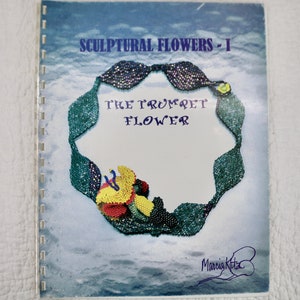 May include: A book titled "Sculptural Flowers - I" with a beaded flower design on the cover. The flower is made of green, purple, and yellow beads and is shaped like a trumpet. The book is by Marcia Kitts.
